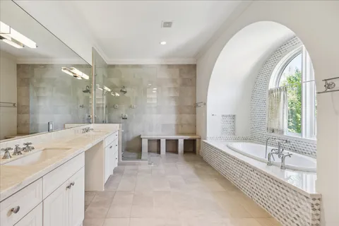 a large spacious bathroom with a tub double vanity sink a mirror and a shower