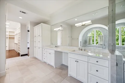 a bathroom with a granite countertop double vanity sink a mirror a bathtub and window