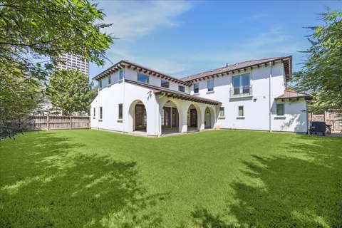 a view of a white house next to a yard with big trees