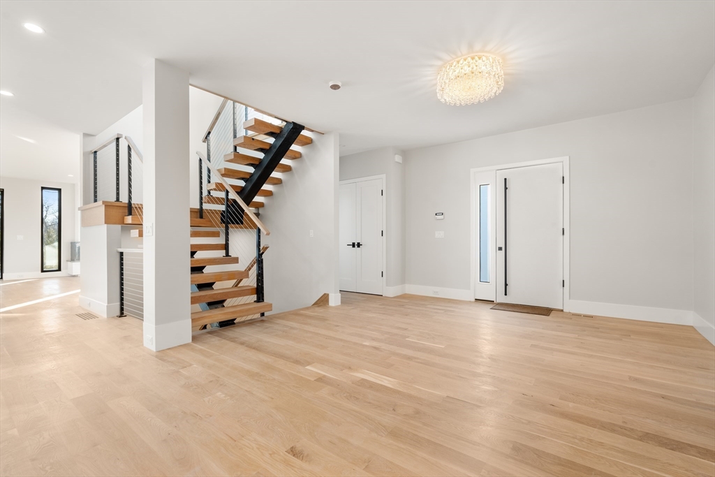 265 Varick Road Newton, MA 02468 - Photo 3 of 32 a view of an empty room with wooden floor and stairs