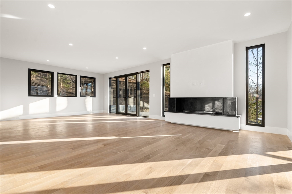 265 Varick Road Newton, MA 02468 - Photo 7 of 32 a view of an empty room with wooden floor and a fireplace
