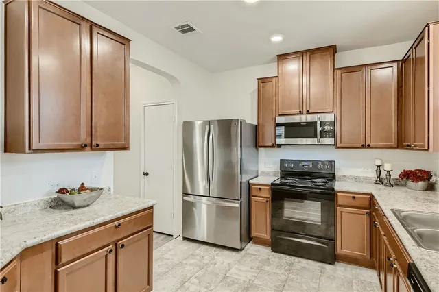 a kitchen with stainless steel appliances granite countertop a refrigerator stove and sink