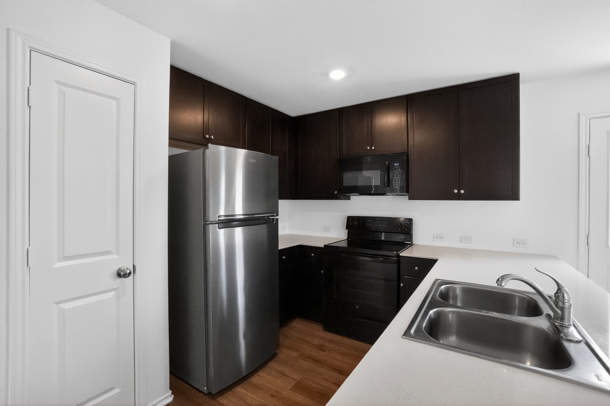 604 Marty Allen Loop Jarrell, TX 76537 - Photo 8 of 15 A well-appointed kitchen features dark cabinetry, bright countertops, and modern stainless steel appliances.