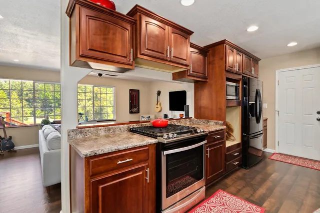 a kitchen with stainless steel appliances granite countertop a refrigerator and a stove top oven
