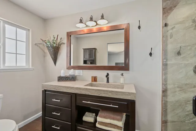 a bathroom with a granite countertop sink a mirror a vanity and a shower