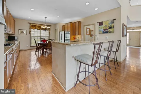a kitchen with stainless steel appliances kitchen island granite countertop a table chairs and a refrigerator