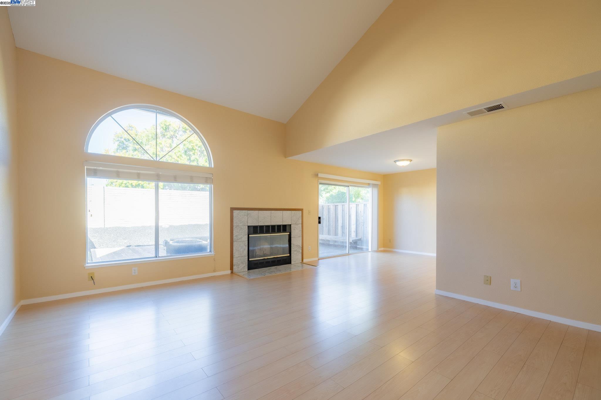 123 Pelican Loop Pittsburg, CA 94565 - Photo 6 of 60 an empty room with wooden floor fireplace and windows