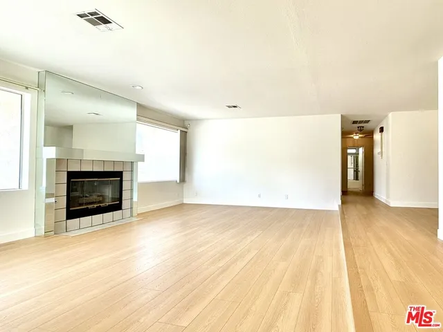 a view of empty room with wooden floor and fireplace
