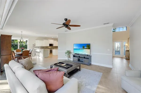 a living room with furniture a flat screen tv and kitchen view