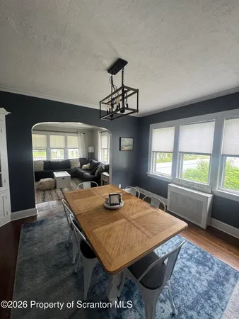 a dining room with wooden floor a chandelier a wooden table and chairs