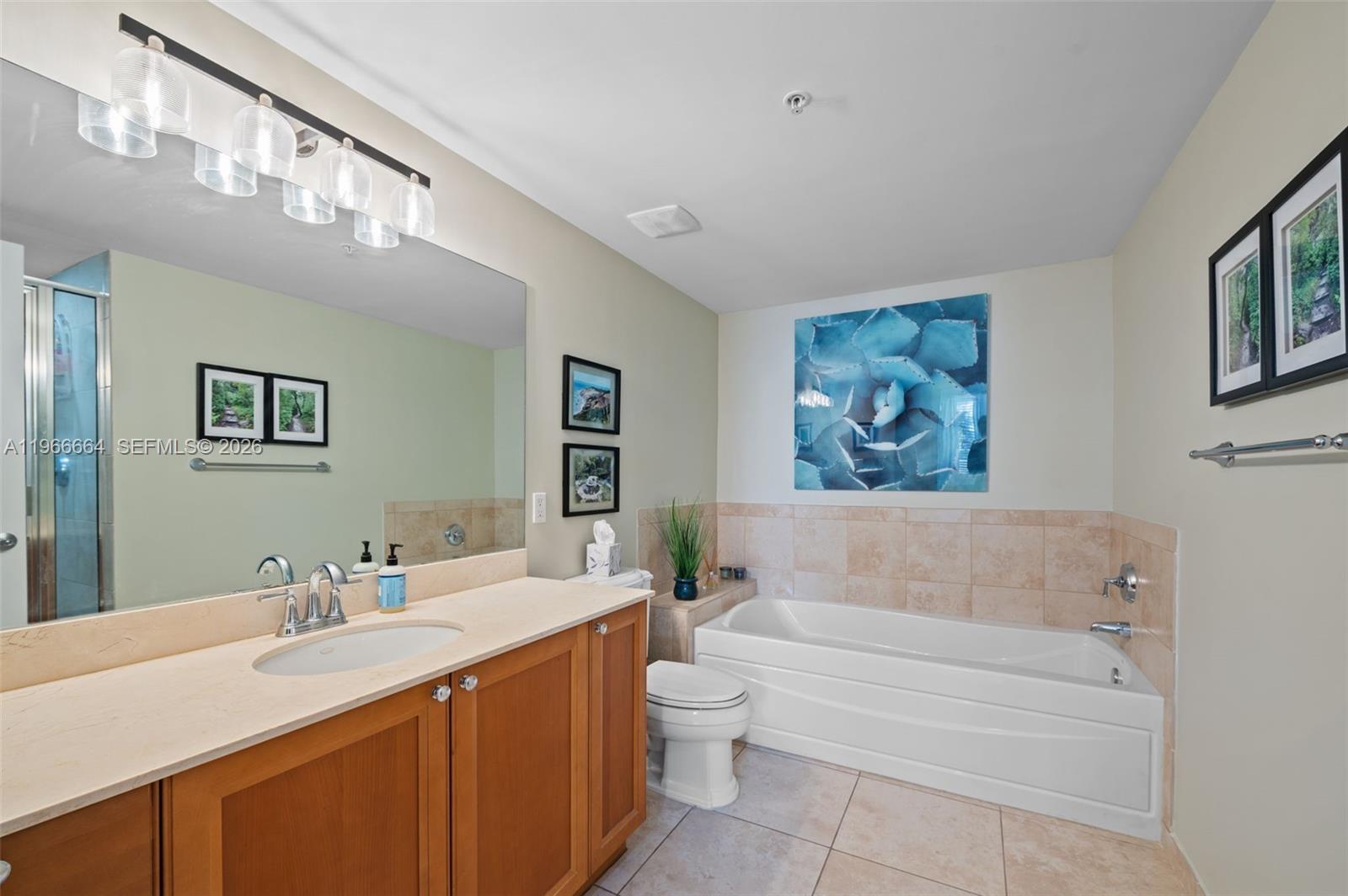 55 Merrick Way, Unit 507 Coral Gables, FL 33134 - Photo 17 of 28 a bathroom with a sink a toilet a mirror a vanity a bathtub and shower