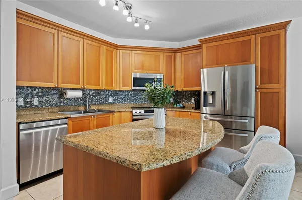 a kitchen with granite countertop a sink refrigerator and cabinets