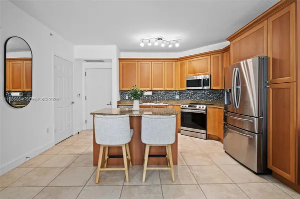 a kitchen with stainless steel appliances a refrigerator a stove a sink dishwasher and a dining table with wooden cabinet