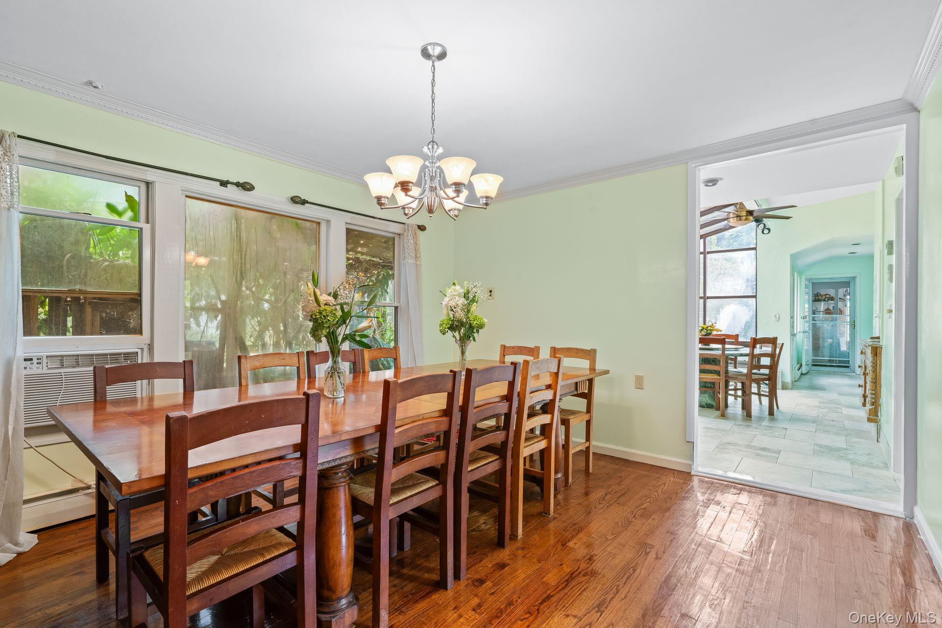 13 Whitney Circle Glen Cove, NY 11542 - Photo 11 of 44 Dining area featuring dark wood-type flooring, crown molding, a chandelier, ceiling fan, and a baseboard heating unit