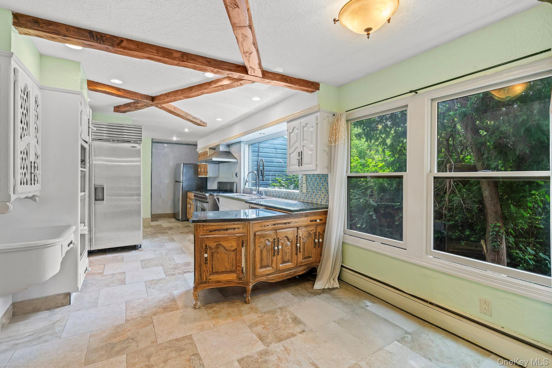 13 Whitney Circle Glen Cove, NY 11542 - Photo 14 of 44 Kitchen with a peninsula, a baseboard heating unit, beamed ceiling, appliances with stainless steel finishes, and tasteful backsplash