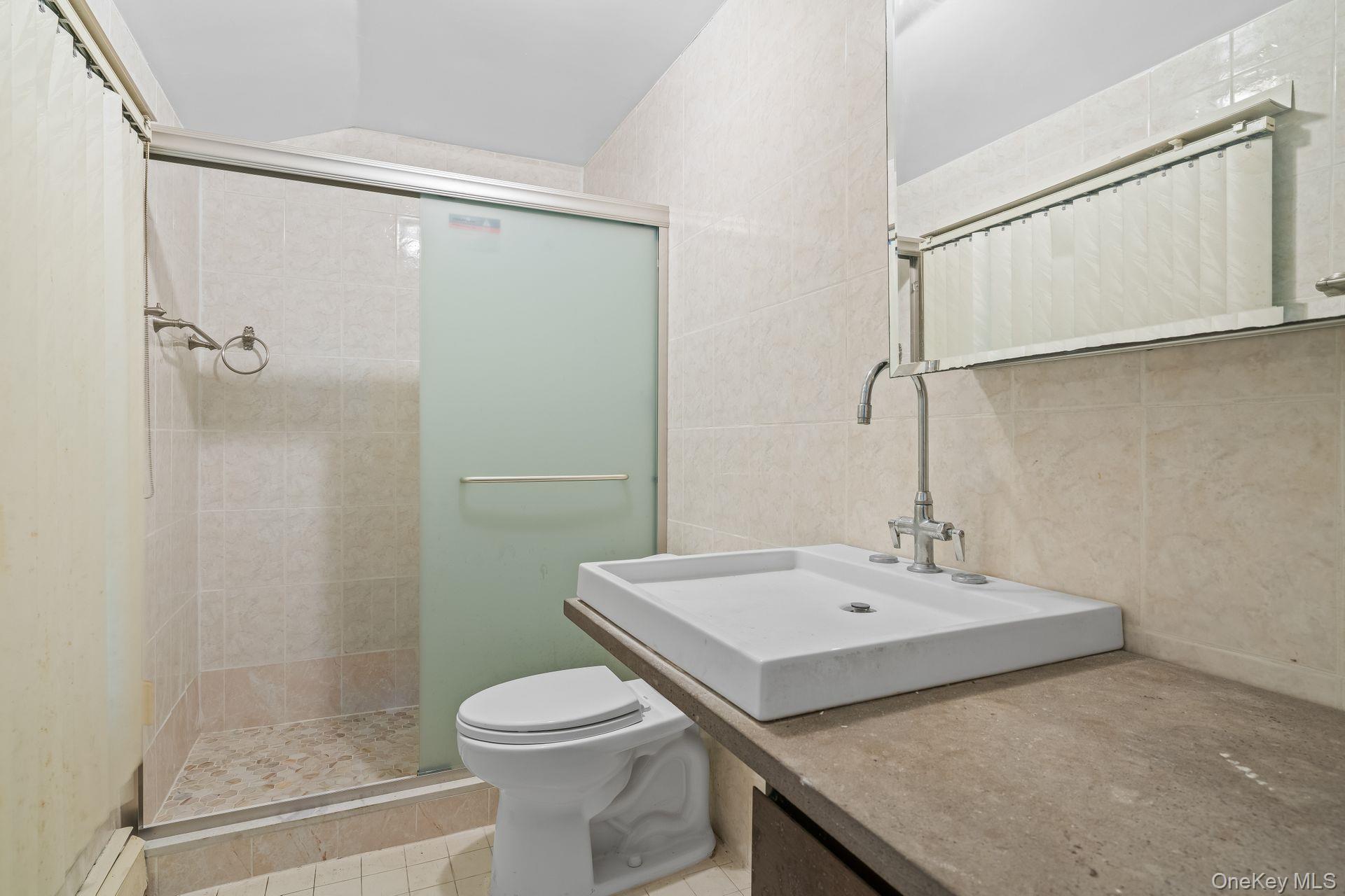 13 Whitney Circle Glen Cove, NY 11542 - Photo 20 of 44 Full bathroom with a stall shower, tile walls, vanity, and light tile patterned floors