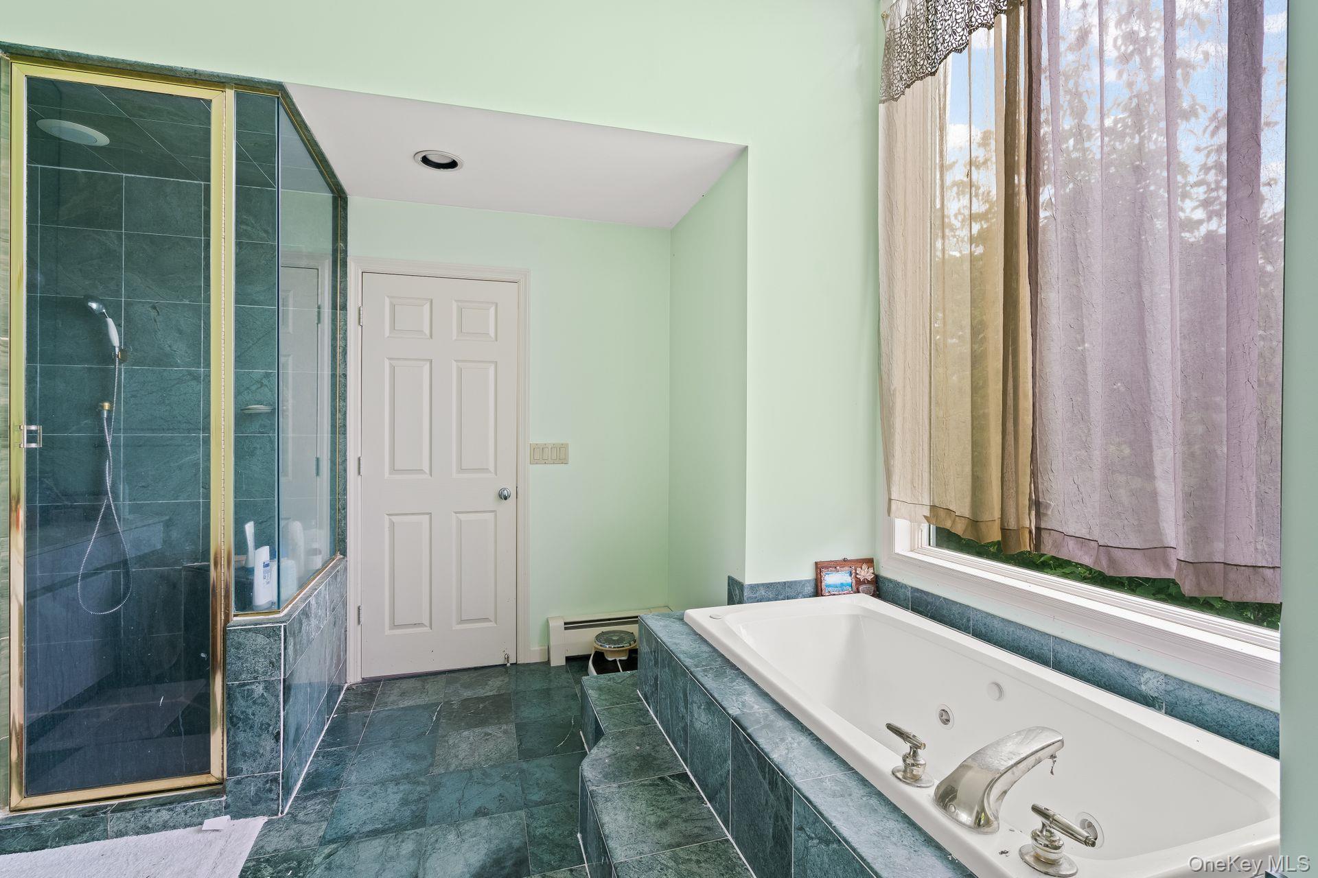 13 Whitney Circle Glen Cove, NY 11542 - Photo 27 of 44 Bathroom featuring a stall shower, a tub with jets, baseboard heating, and dark stone finish floors