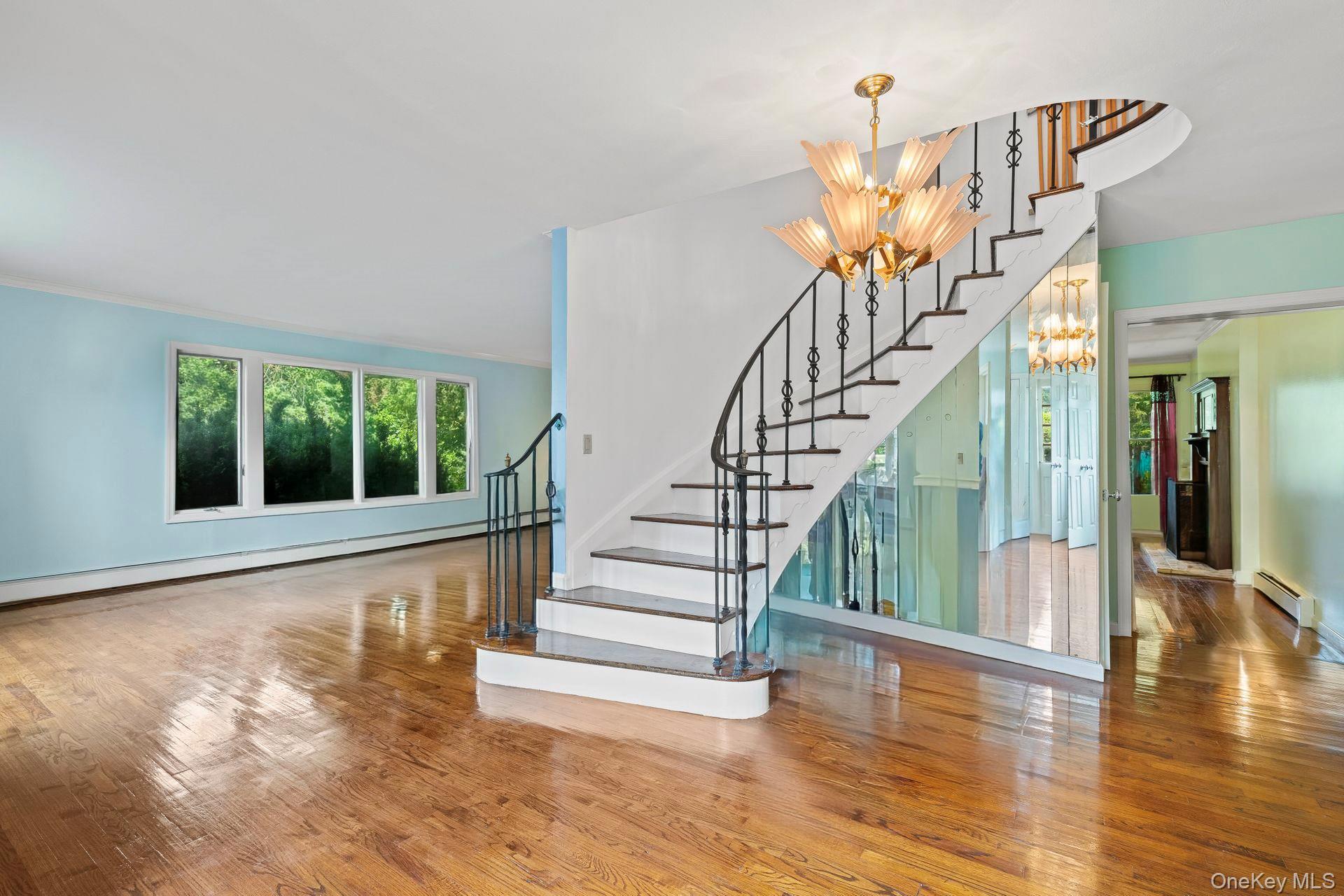13 Whitney Circle Glen Cove, NY 11542 - Photo 5 of 44 Staircase featuring hardwood / wood-style floors, a chandelier, a baseboard radiator, and a baseboard heating unit