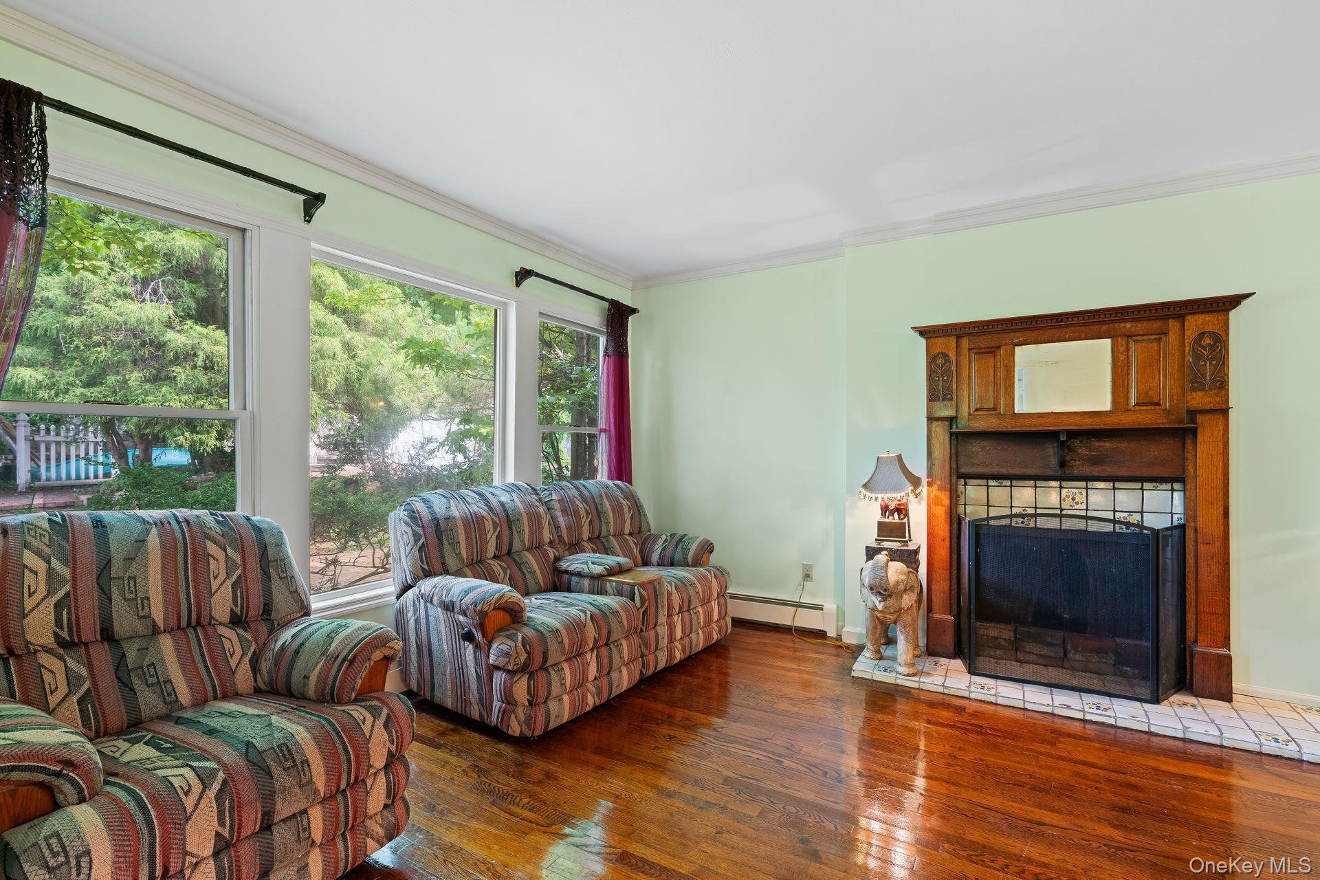 13 Whitney Circle Glen Cove, NY 11542 - Photo 10 of 44 Living area with dark wood-style floors, crown molding, a fireplace, and baseboard heating