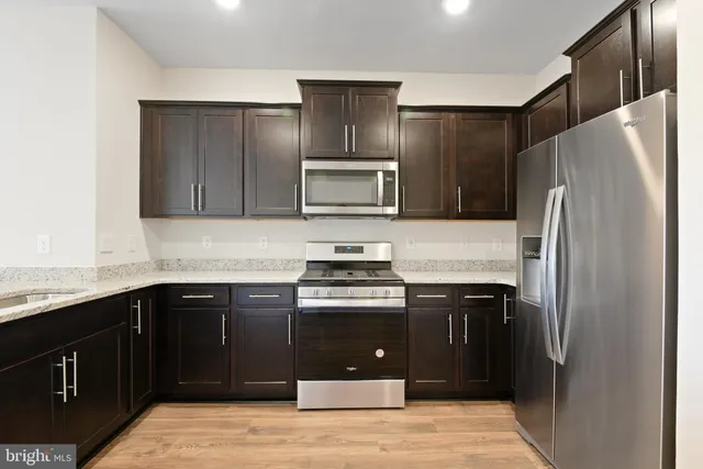 a kitchen with stainless steel appliances granite countertop wooden cabinets a stove top oven and granite counter tops
