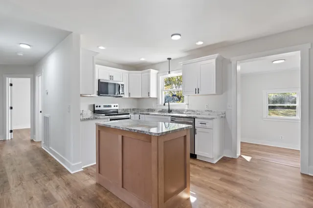 a kitchen with stainless steel appliances granite countertop a stove top oven a sink and a refrigerator