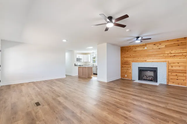a view of a livingroom with a fireplace a ceiling fan and window