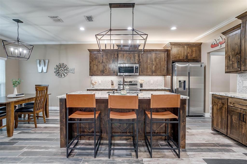 850 McClendon Walker Road Aledo, TX 76008 - Photo 12 of 38 a dining room with stainless steel appliances kitchen island granite countertop a table chairs and a refrigerator