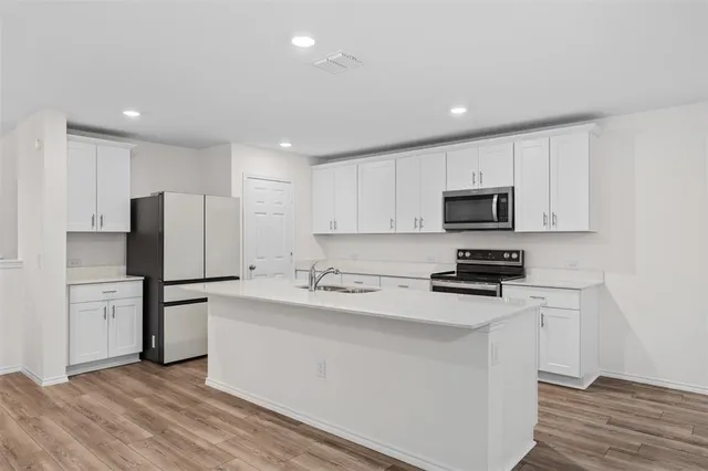 a kitchen with kitchen island white cabinets and stainless steel appliances