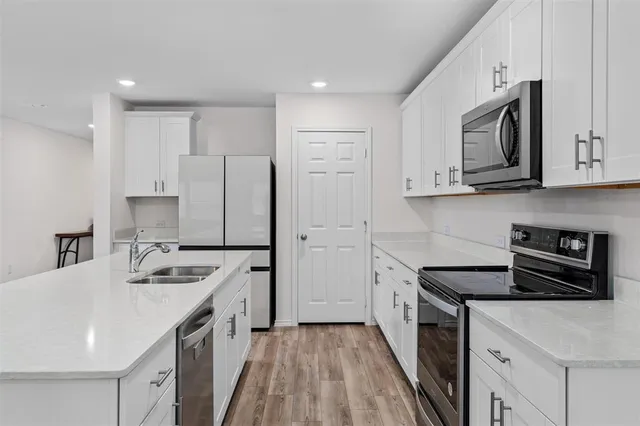 a kitchen with a refrigerator a stove top oven a sink and cabinets
