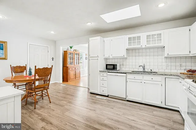 a kitchen with stainless steel appliances granite countertop a white cabinets and wooden floors