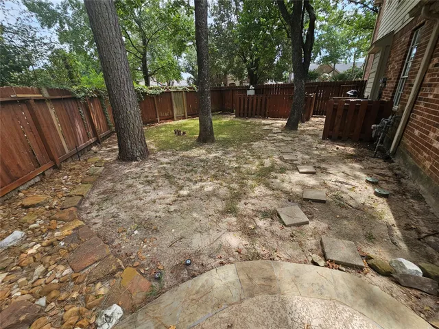 a view of backyard with green space and wooden fence