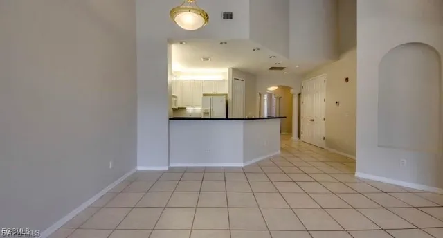 a view of a refrigerator in kitchen and an empty room