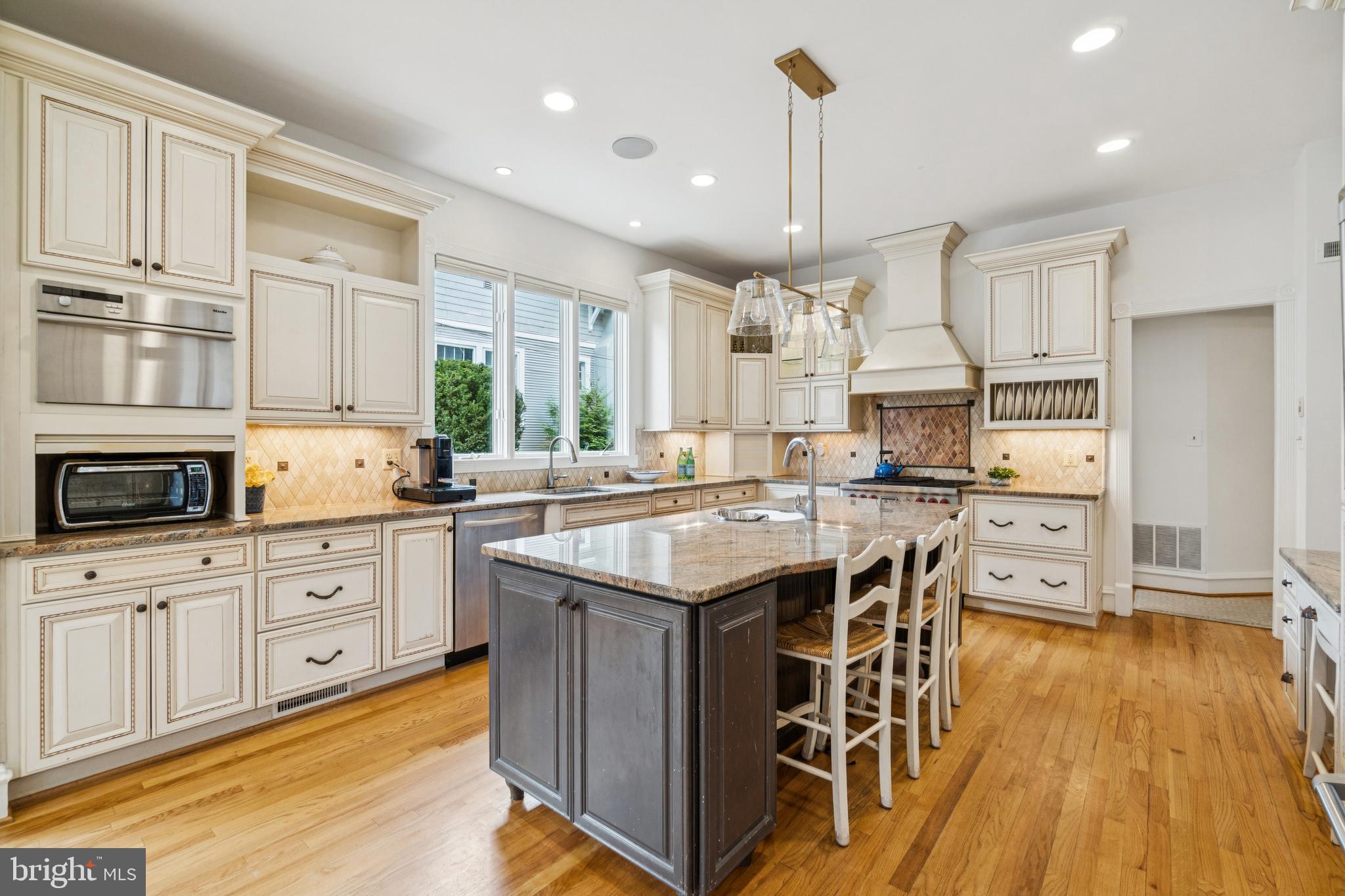 4406 Stanford Street Chevy Chase, MD 20815 - Photo 12 of 49 a kitchen with stainless steel appliances granite countertop a stove top oven a refrigerator a sink and white cabinets with wooden floor
