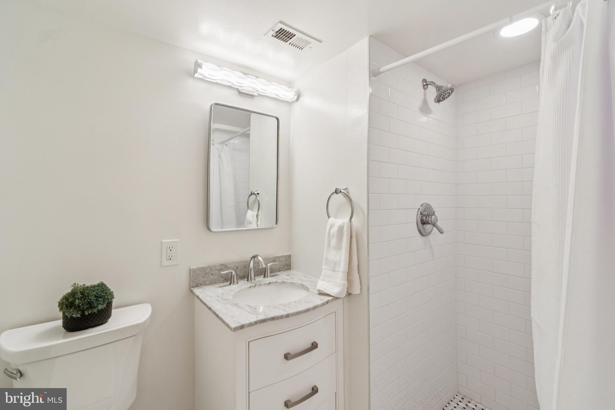 4406 Stanford Street Chevy Chase, MD 20815 - Photo 40 of 49 a bathroom with a granite countertop sink a toilet and a mirror
