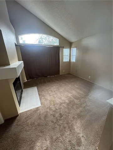 an empty room with a fireplace and windows