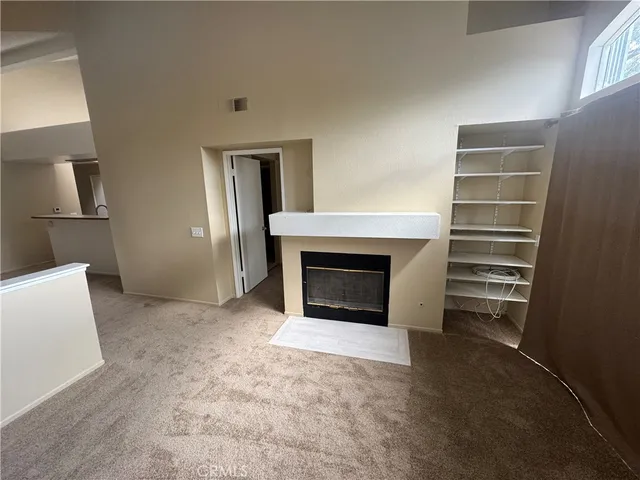 a view of kitchen and empty room with fireplace