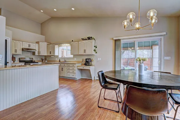 a kitchen with stainless steel appliances a dining table chairs and stove