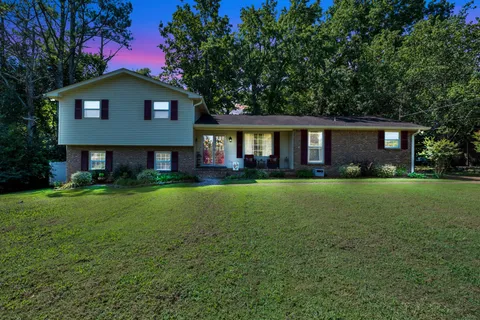 a front view of a house with a yard and green space
