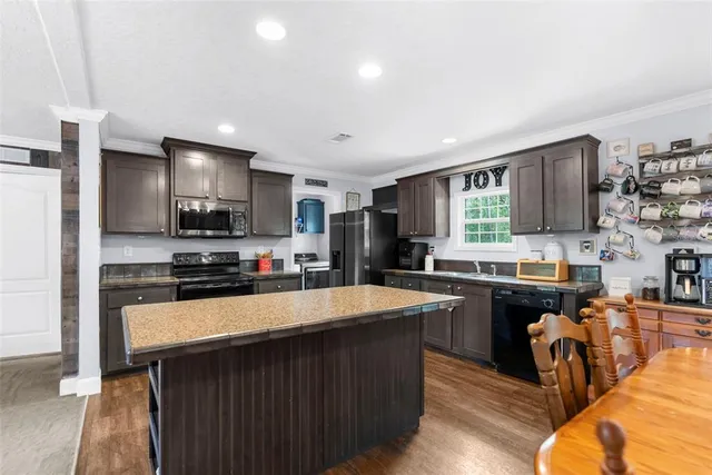 a large kitchen with granite countertop a large counter top stainless steel appliances and cabinets