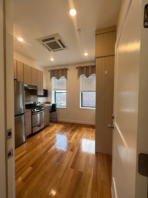 21 5th Street, Unit 26 Chelsea, MA 02150 - Photo 3 of 11 a kitchen with granite countertop a refrigerator and wooden floor