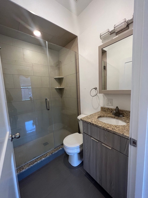 21 5th Street, Unit 26 Chelsea, MA 02150 - Photo 5 of 11 a bathroom with a granite countertop sink a toilet a mirror and shower