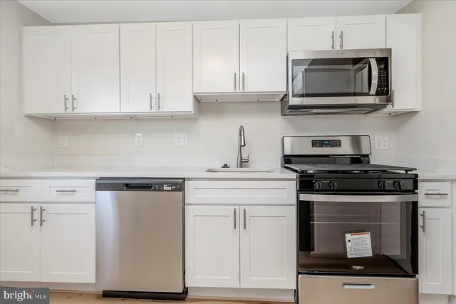 a kitchen with stainless steel appliances granite countertop white cabinets stove top oven and microwave