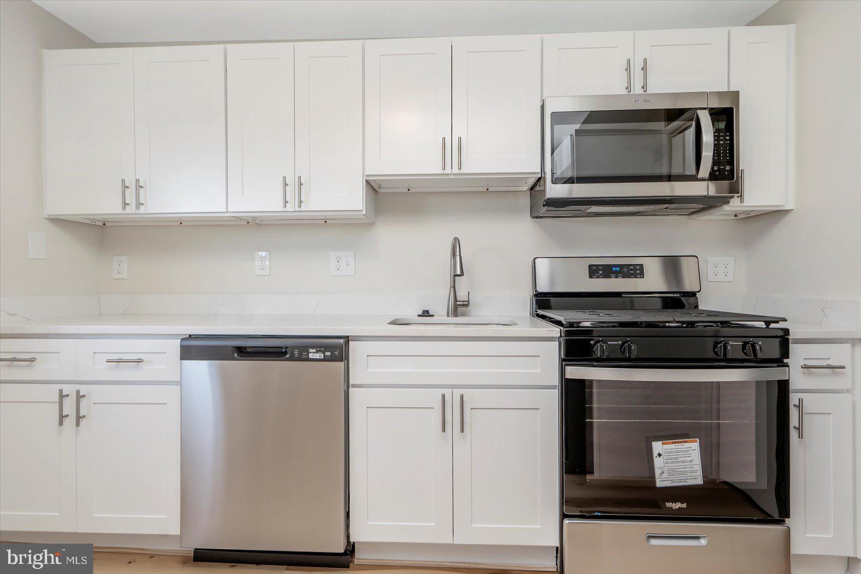 4322 Annapolis Road Baltimore, MD 21227 - Photo 12 of 28 a kitchen with stainless steel appliances granite countertop white cabinets stove top oven and microwave