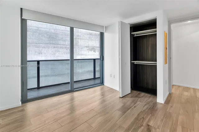 a view of a hallway with wooden floor and a bathroom