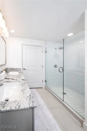 a bathroom with a granite countertop sink a mirror and shower