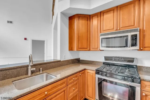 a kitchen with granite countertop a sink stainless steel appliances and cabinets