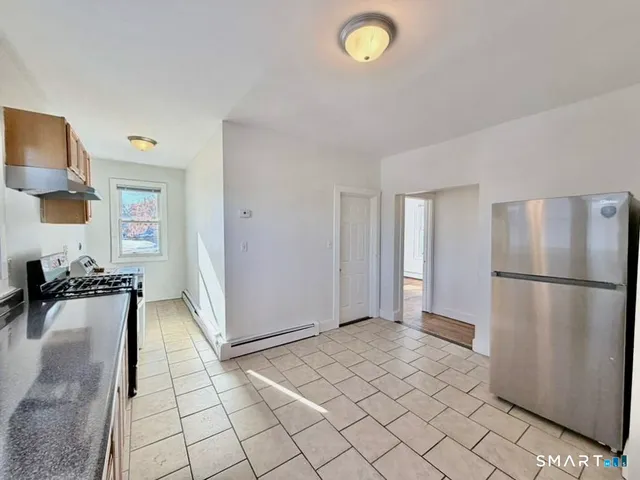 a large white kitchen with granite countertop a sink and cabinets
