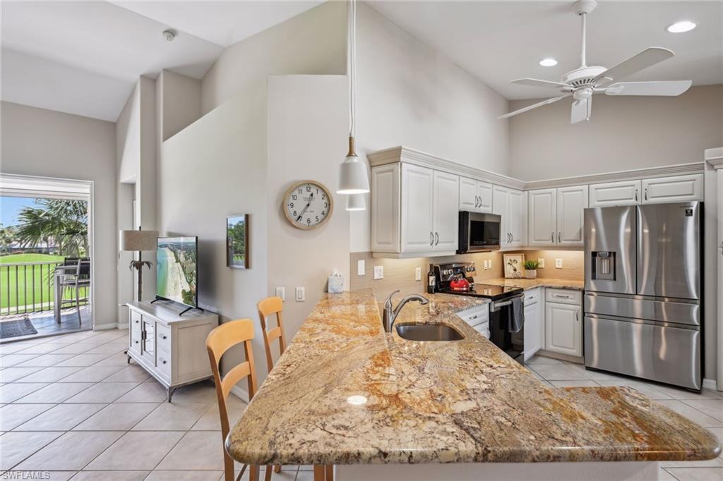 9030 Spring Run Boulevard, Unit 508 Estero, FL 34135 - Photo 6 of 50 a kitchen with stainless steel appliances kitchen island granite countertop a refrigerator stove top oven and sink