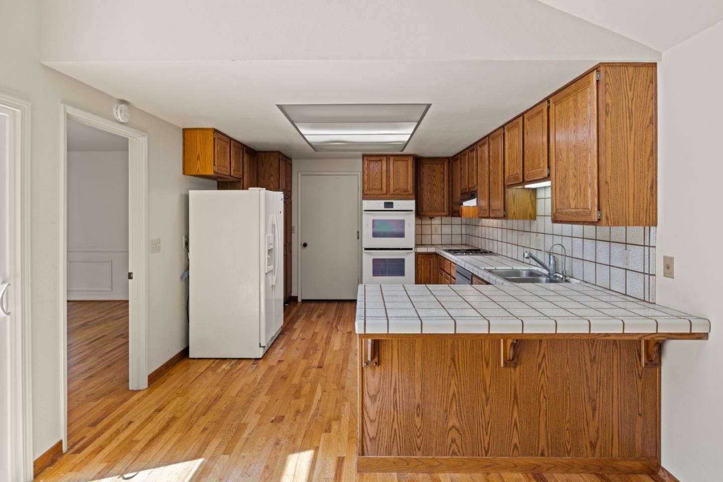 14220 Mountain Quail Road Salinas, CA 93908 - Photo 36 of 74 a kitchen with a refrigerator a stove top oven a sink and dishwasher with wooden floor