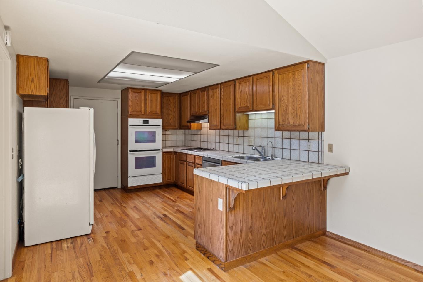14220 Mountain Quail Road Salinas, CA 93908 - Photo 37 of 74 a kitchen with a sink a refrigerator a stove and wooden floor